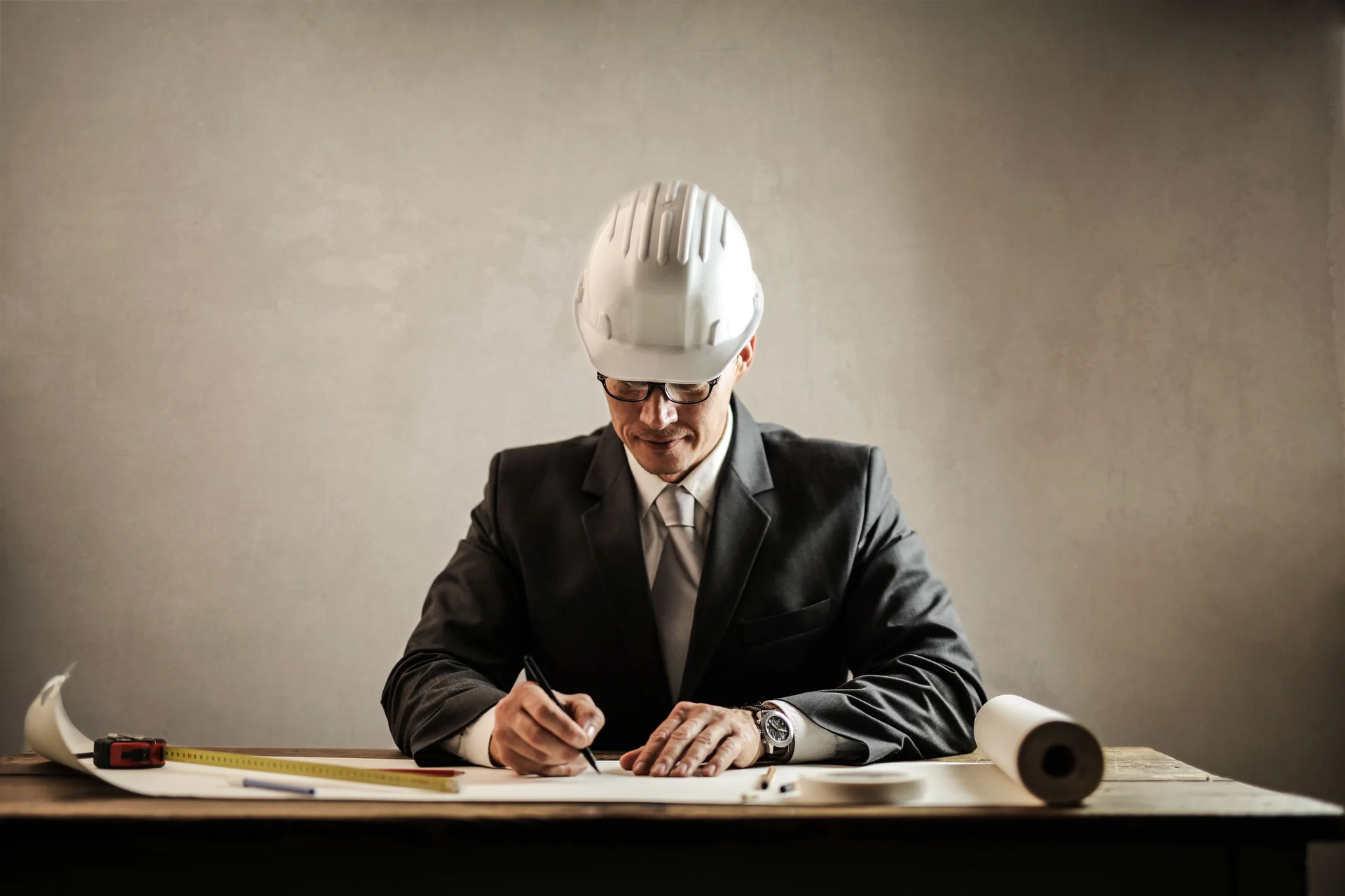 Engineer in a white hard hat working on plans at a desk